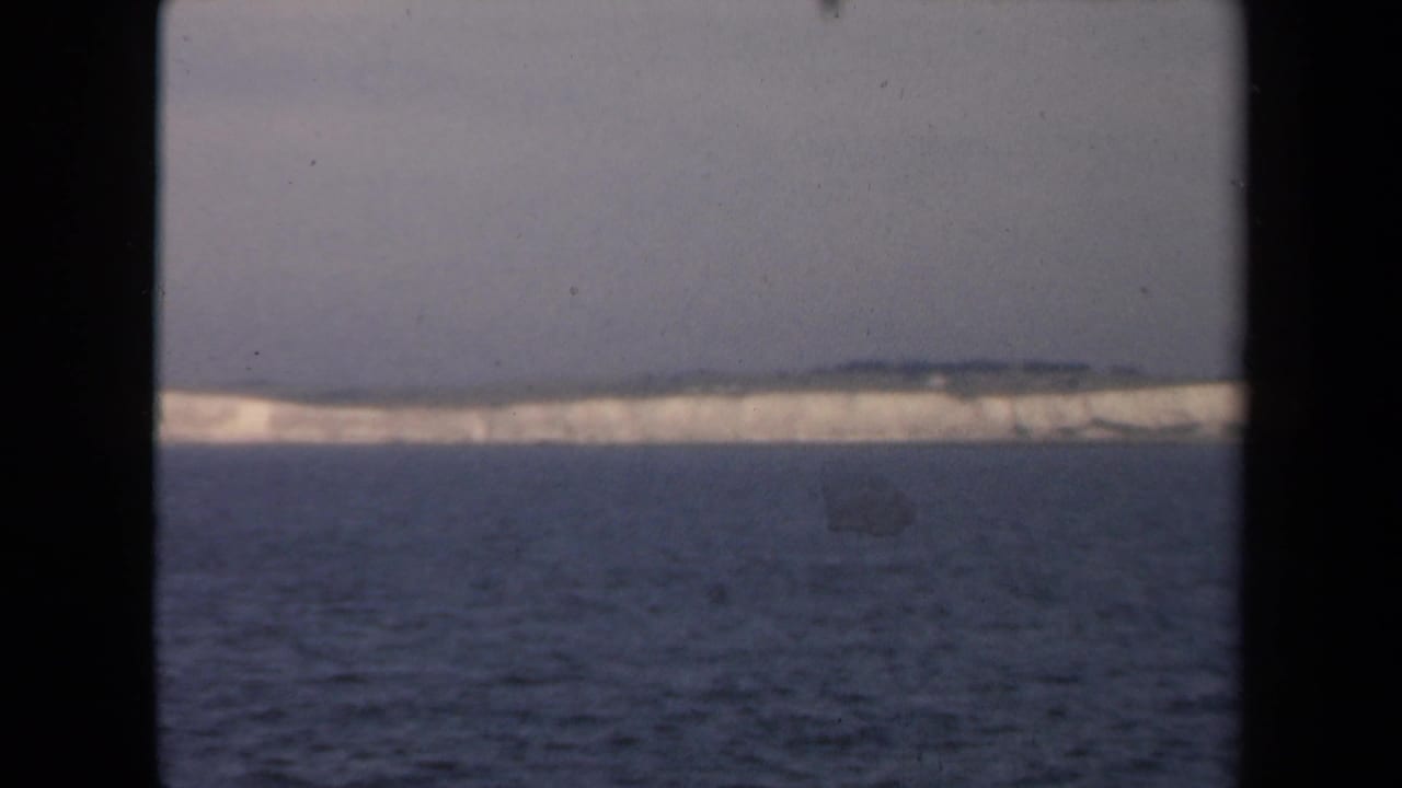 Distant pale ice or coastline across dark water under a grey sky.