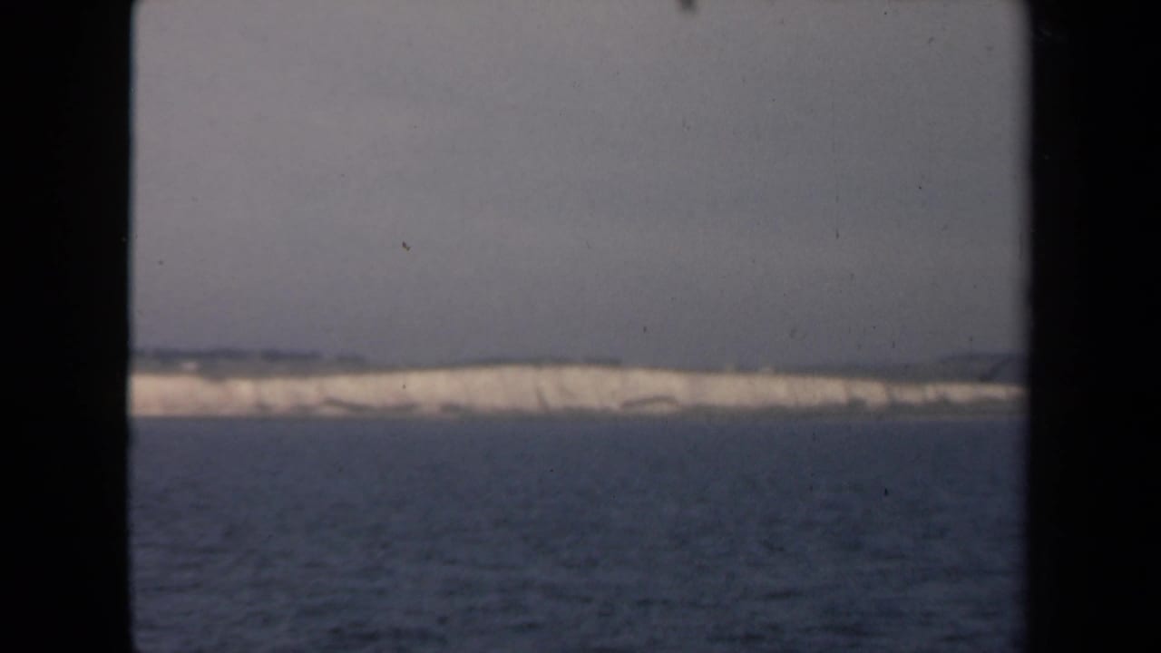 Distant pale shoreline across open water, seen through dark window framing.