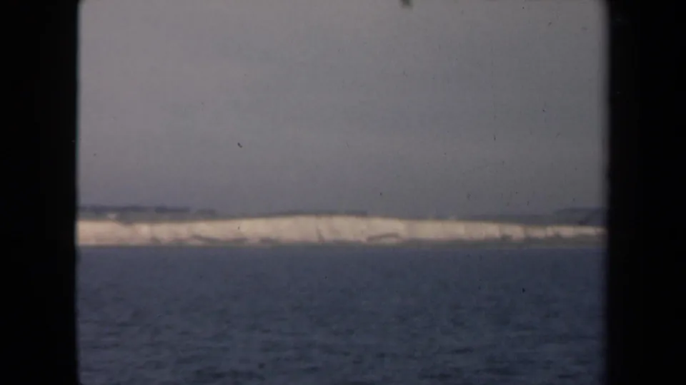 1946 Netherlands coastal view across open water, framed by the dark edges of a vessel window or porthole.