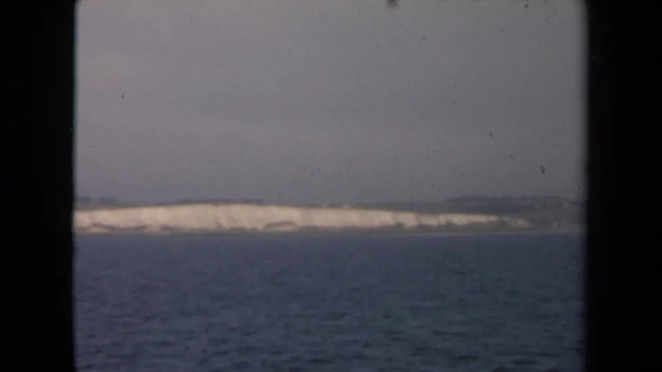 A muted 1946 Netherlands coastal view shows open sea, a pale shoreline, and dark window framing from aboard a vessel.