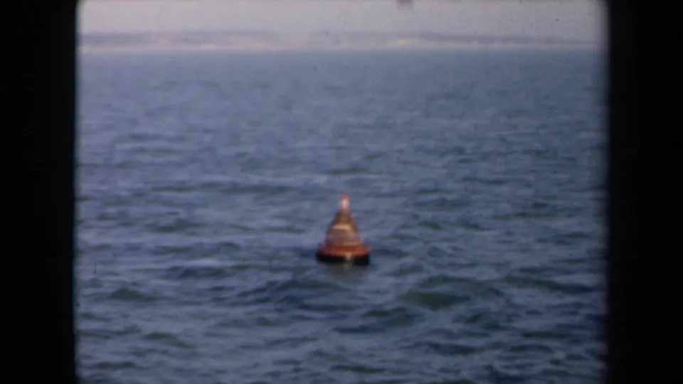 1946 Netherlands 8mm frame showing a small orange conical buoy on open water, seen through dark film-gate edges.