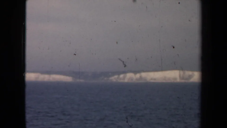 Hazy 1946 8mm view of ocean and a pale distant coast, with black frame edges and visible archival dust.