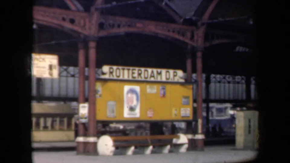 1946 Netherlands frame with Rotterdam D.P. station signage, yellow notice board, bench and cast-iron canopy supports.