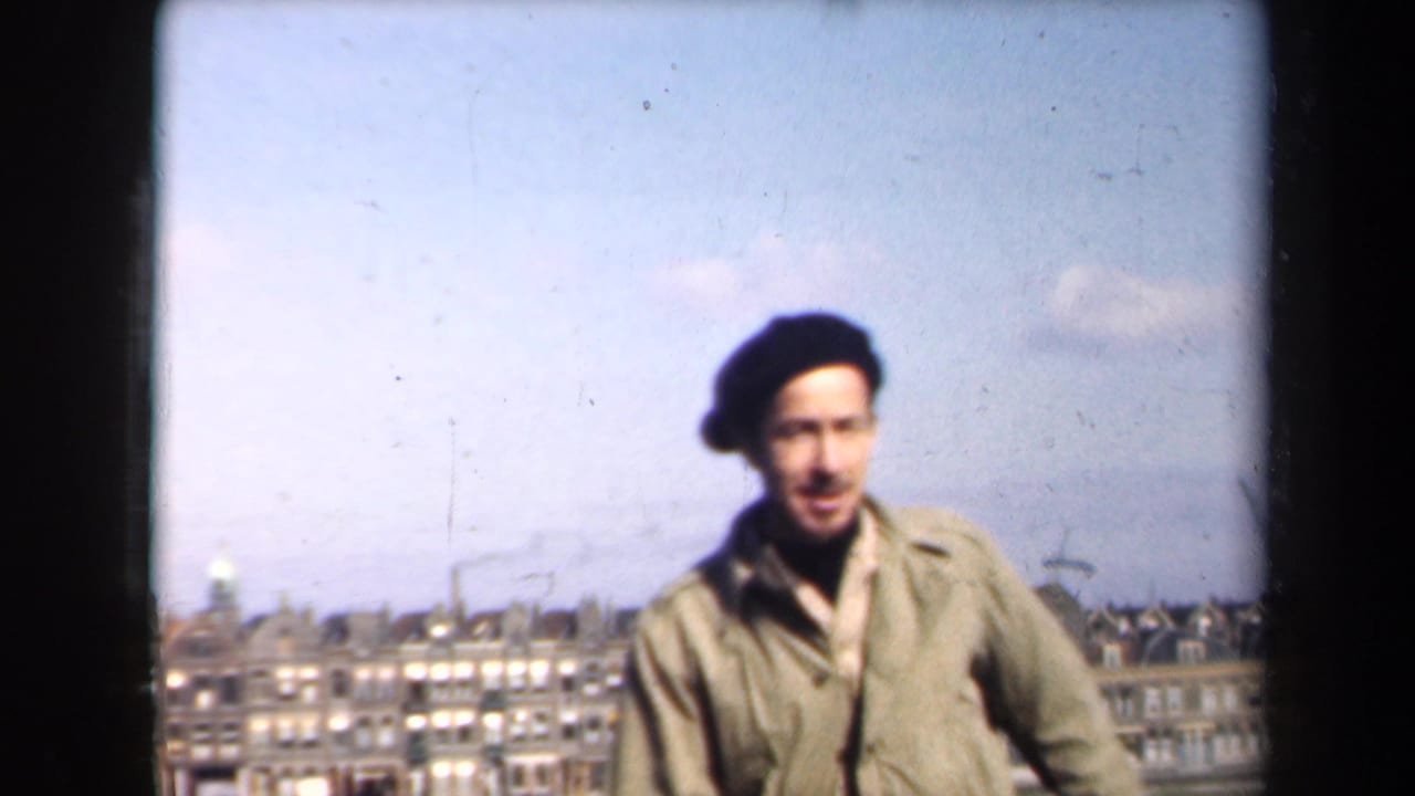 In 1946 Netherlands home-movie footage, a man in a beret stands on a rooftop before a distant cityscape and pale sky.