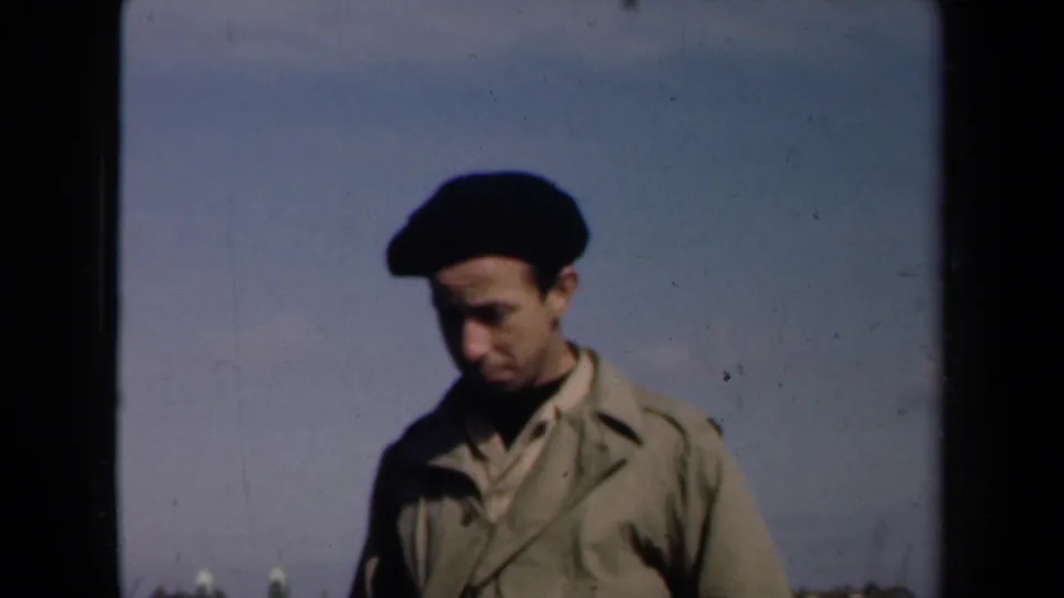 The beret-wearing man looks down in the 1946 Netherlands rooftop shot, with city rooftops low in the frame.