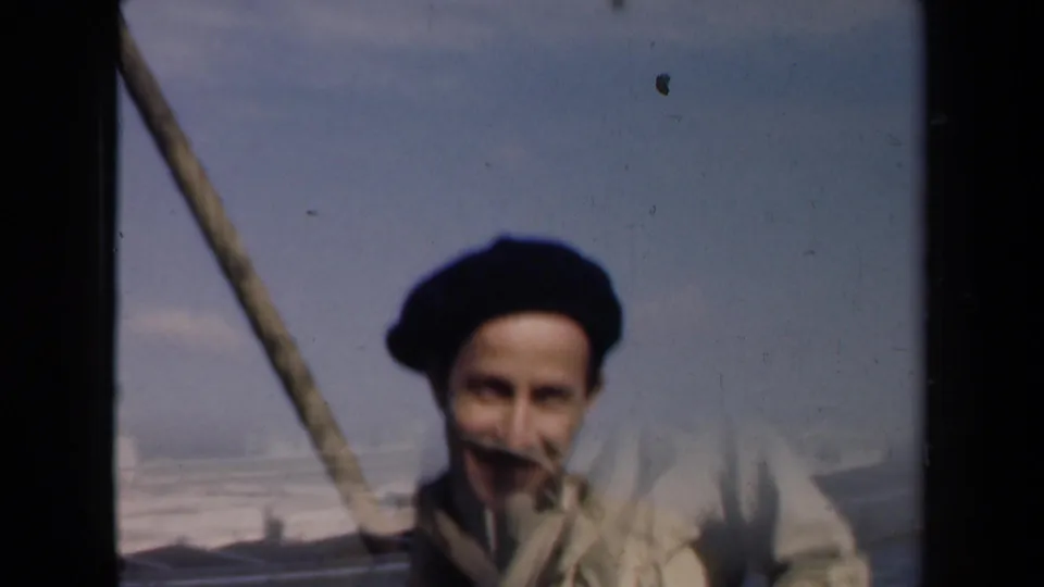 The man remains on the rooftop, partly crossed by a diagonal pole or line, with the Dutch city horizon faintly visible behind him.