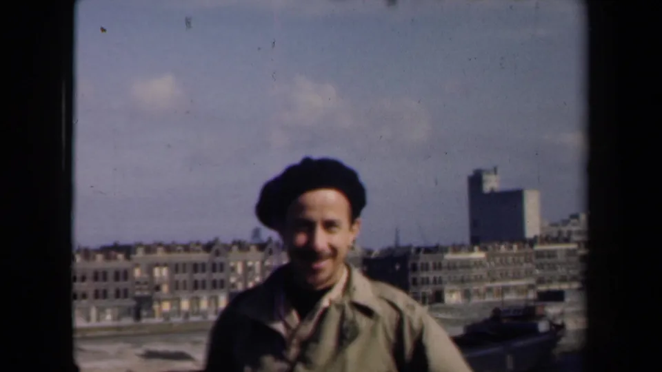 The adult man remains centered in the 1946 Netherlands scene, with traditional buildings, a modern high-rise, and soft 8mm grain visible.