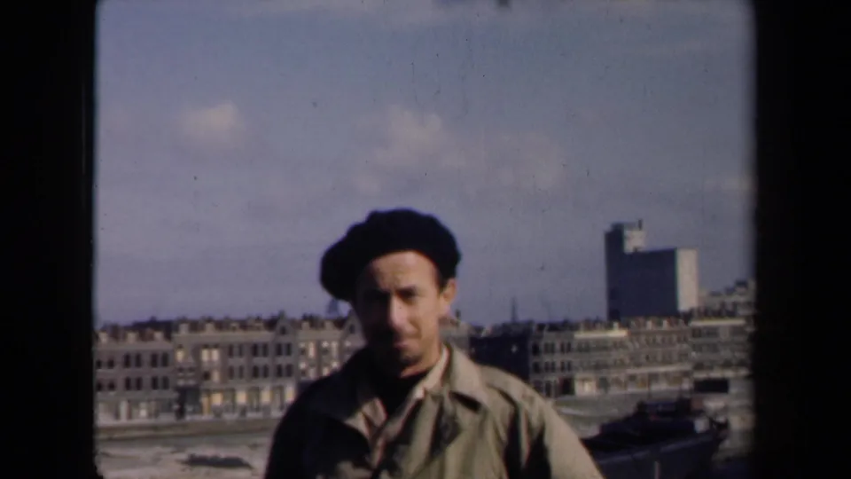 At the end of the clip, the man looks toward the camera in the Netherlands city setting, with skyline details and film-frame edges visible.