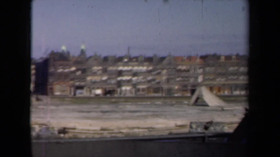 Wide 1946 Netherlands city view showing rows of buildings beyond open damaged ground and a waterfront edge.