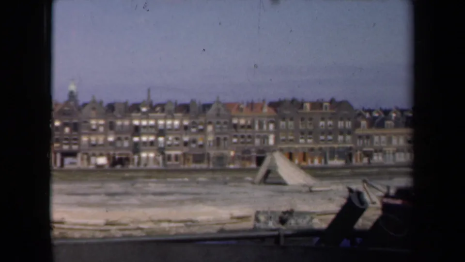 Wide postwar Netherlands cityscape with damaged open ground, waterfront edge, and rows of urban buildings in 1946.