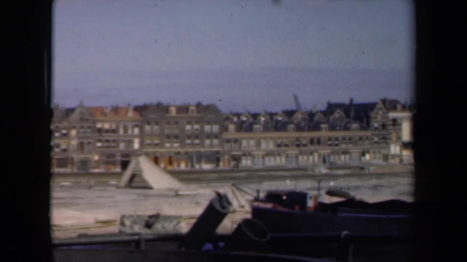 Soft 1946 Netherlands frame showing canal-side architecture, a triangular wooden structure, and a dark foreground boat or barge.