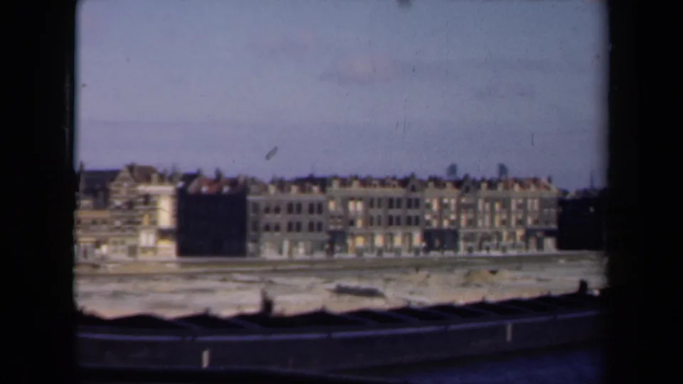 1946 Netherlands 8mm frame showing a row of waterfront facades across an empty pale shoreline, with dark framing at the edges.