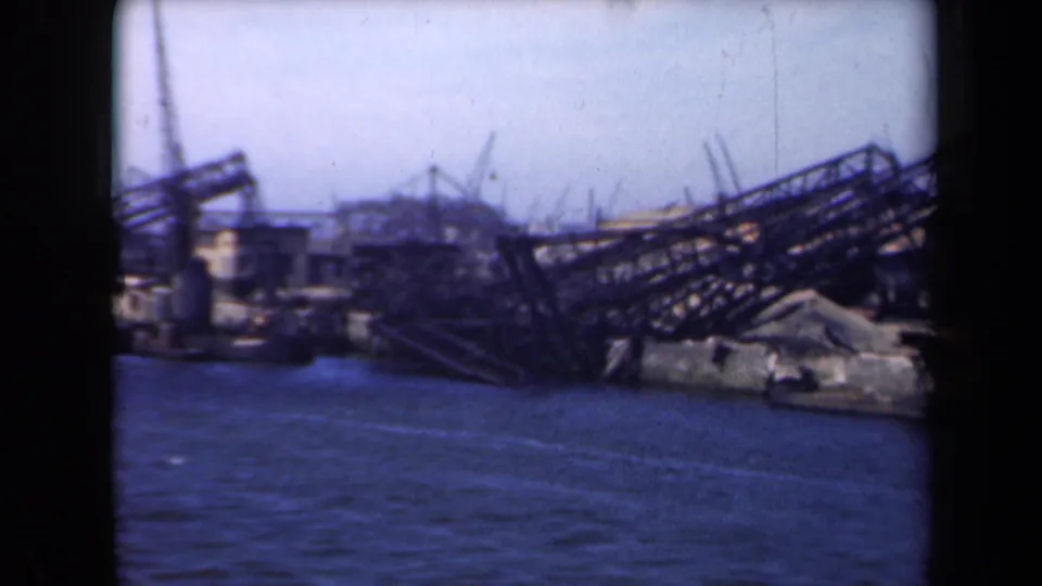 1946 Netherlands 8mm frame showing a damaged port edge with collapsed framework and a small vessel near the shoreline.