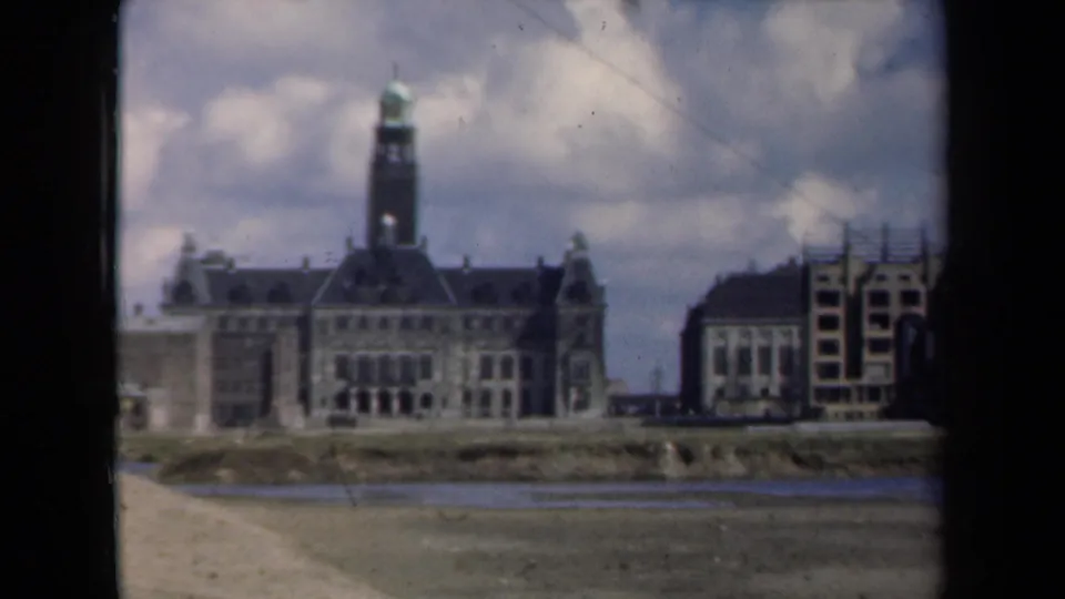 A closer framing of the Dutch riverside architecture shows the central towered building and neighboring structures under a soft cloudy sky.