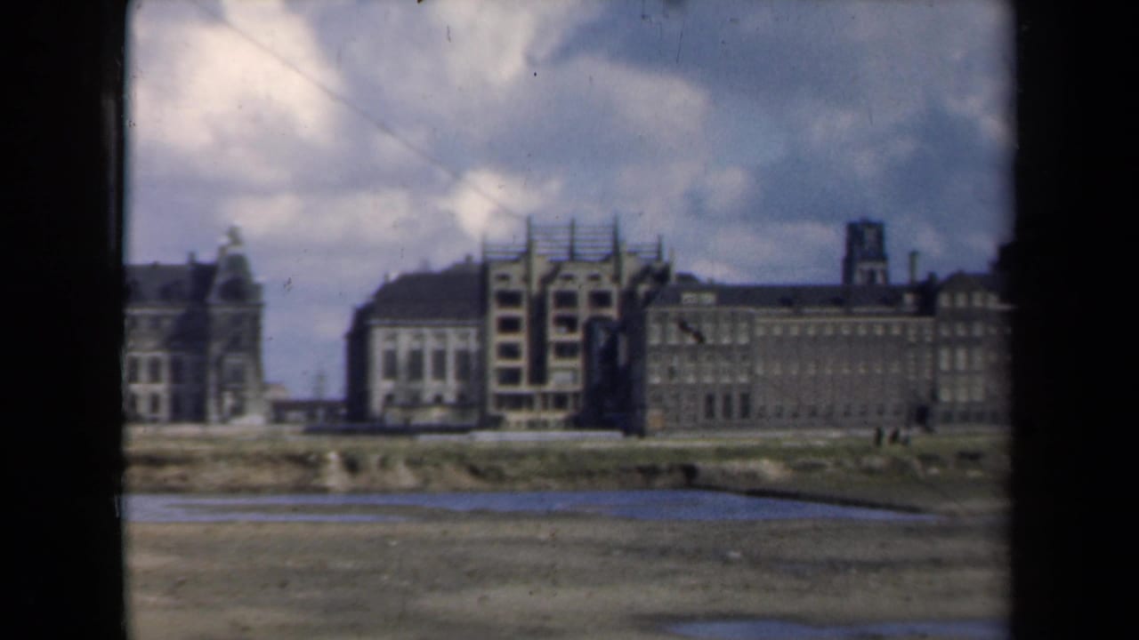 Panoramic view of scaffolded buildings, tower shapes, cloudy sky, and muddy ground.