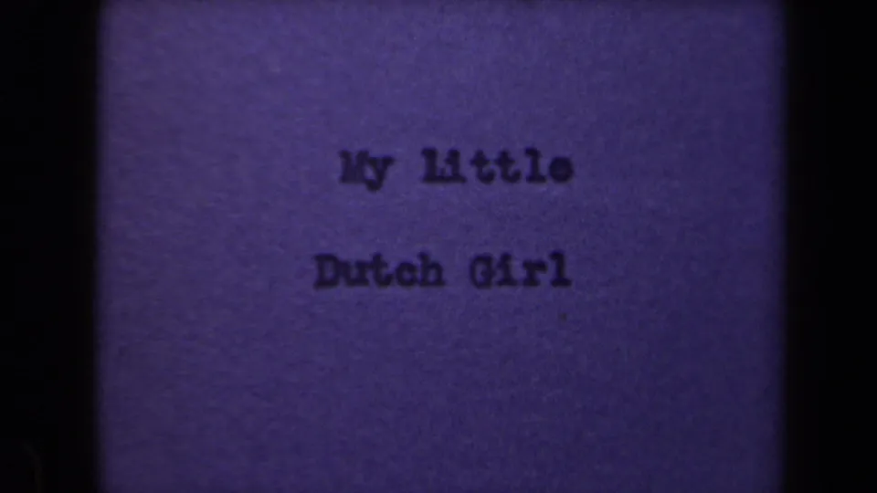 Purple-tinted 8mm frame from the Netherlands clip showing the typewritten title My Little Dutch Girl on a textured card.