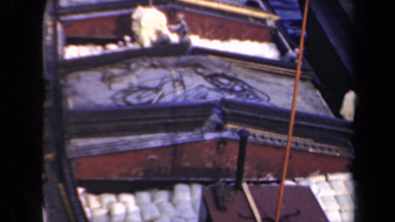 1946 Netherlands 8mm frame showing workers near white cylindrical cargo on a weathered wooden barge deck.