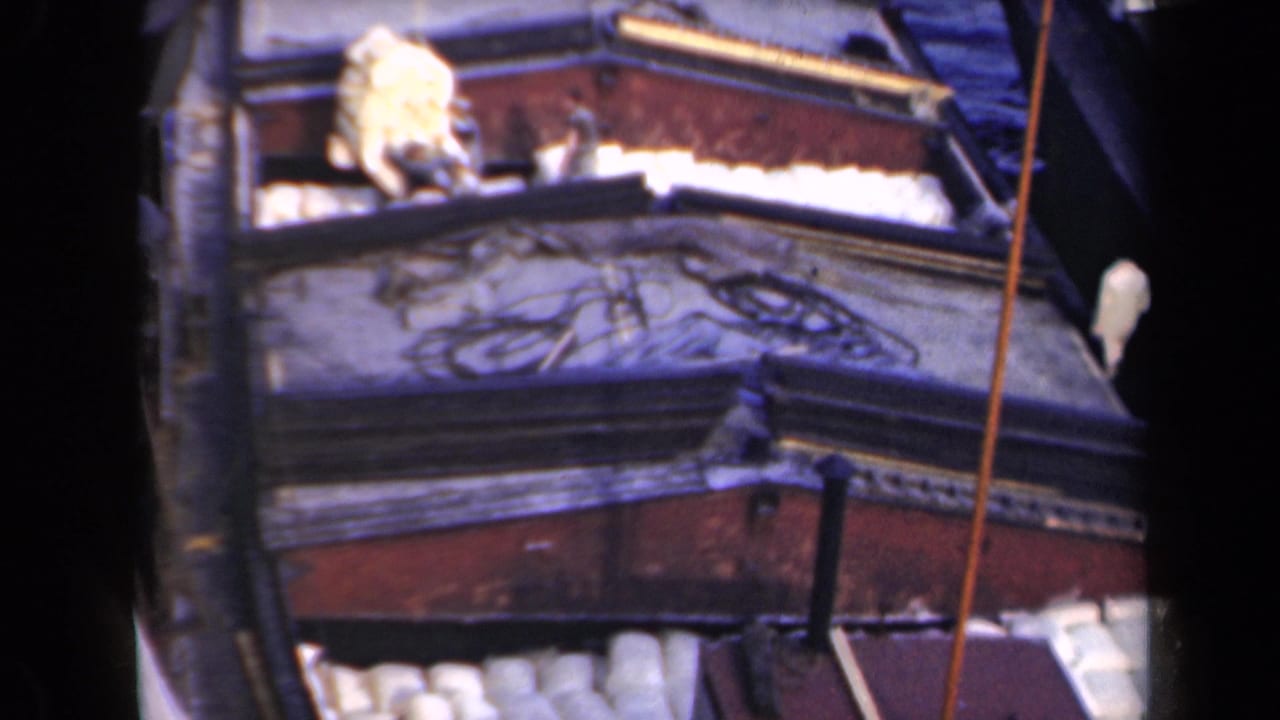 Barge deck with workers, white cargo, and a vertical pole.