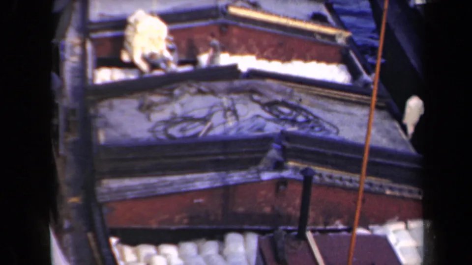 1946 Netherlands home-movie frame of a cargo barge deck with workers, white cargo, painted wood, and rigging.