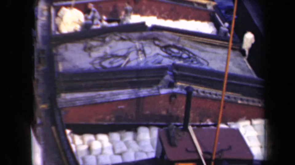 1946 Netherlands 8mm frame with an elevated view of white cylindrical cargo, workers, and the barge structure.