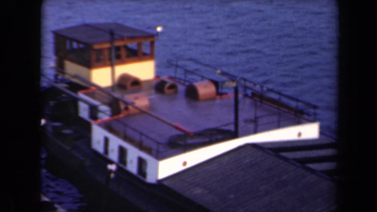 Small yellow-and-white boat with a wooden cabin rocks on blue water beneath a dark foreground structure.