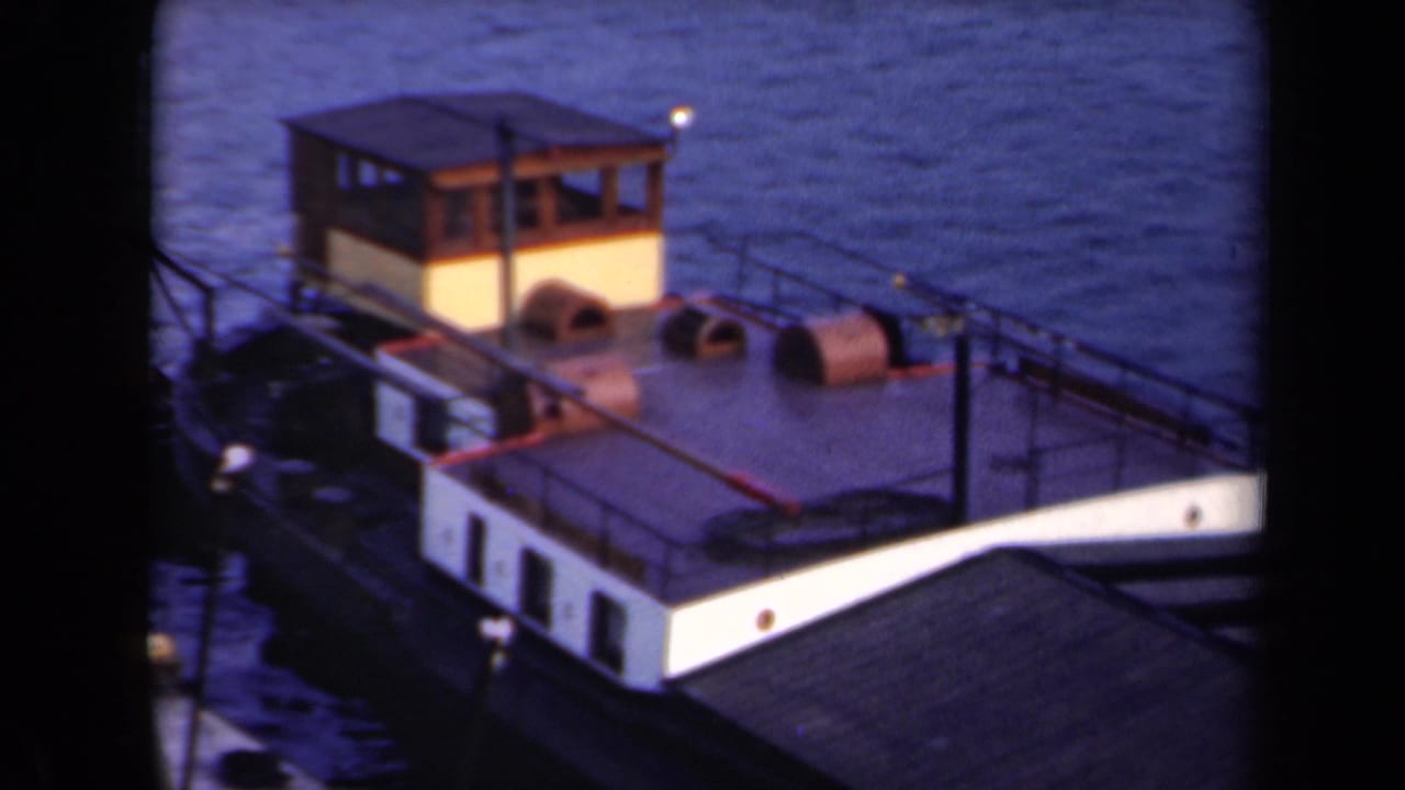 1946 Netherlands 8mm frame of a small cabin boat on calm water, with the pale hull, railings, and deck equipment still visible from above.