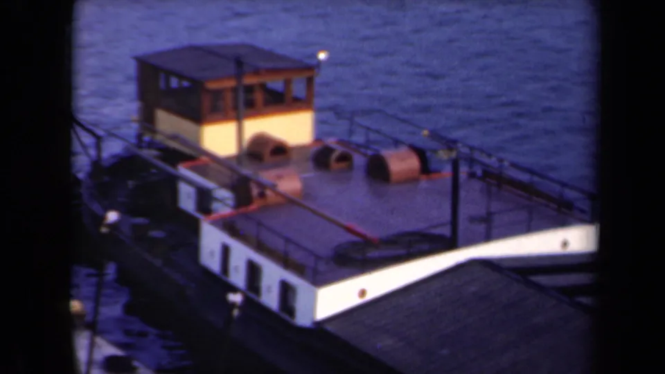 1946 Netherlands 8mm frame of a small cabin boat on calm water, with the pale hull, railings, and deck equipment still visible from above.