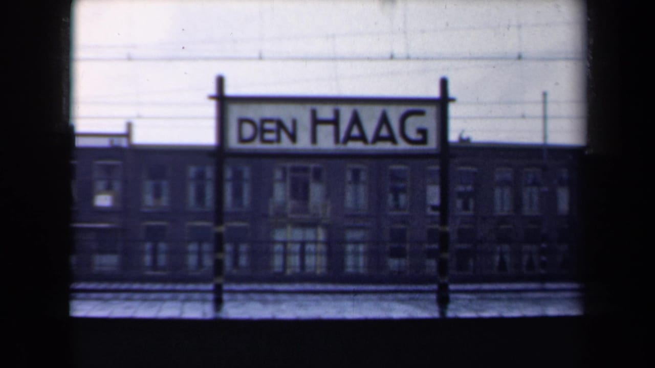 Den Haag station sign seen beside a brick building from a moving train.