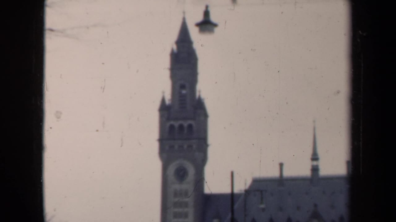 1946 Netherlands 8mm frame showing a Gothic-style clock tower and roofline, with soft focus and dark scan edges.