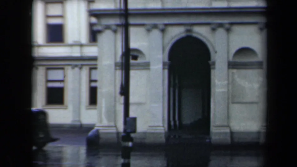 Street-level 1946 view of the palace entrance area, showing the arched doorway, windows, lamppost, and rain-darkened pavement.