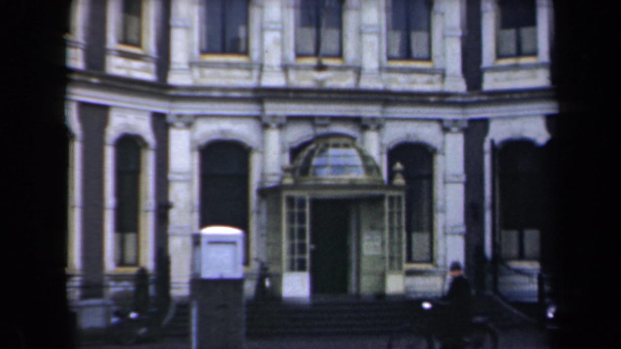 Building entrance and arched windows with a distant pedestrian at the right edge.