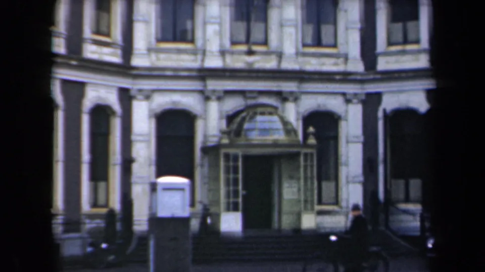 1946 Netherlands street view of the same formal facade, glass portico, steps, and a small distant pedestrian near the right side.
