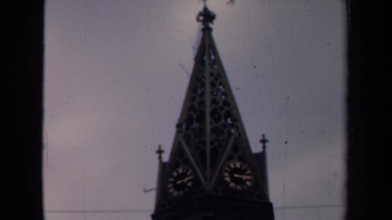 Church spire with clock faces framed near the top of the film image.