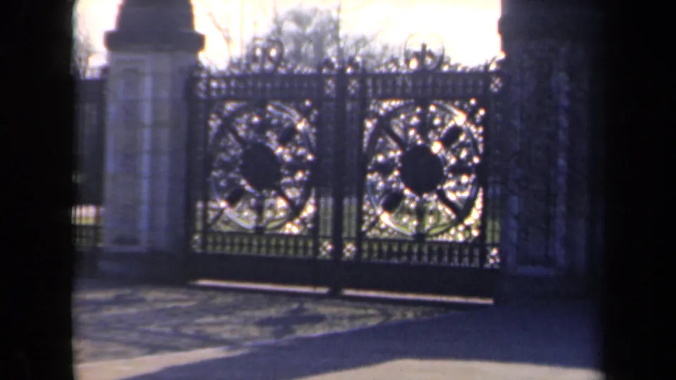 The shot shifts to a closed wrought-iron estate gate with circular ornament and stone pillars in the Netherlands footage.