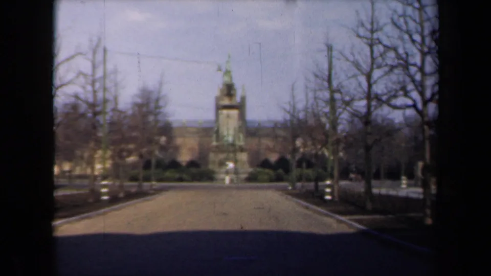 1946 Netherlands frame showing a distant tower or monument at the end of a path, with bare trees and muted 8mm film color.