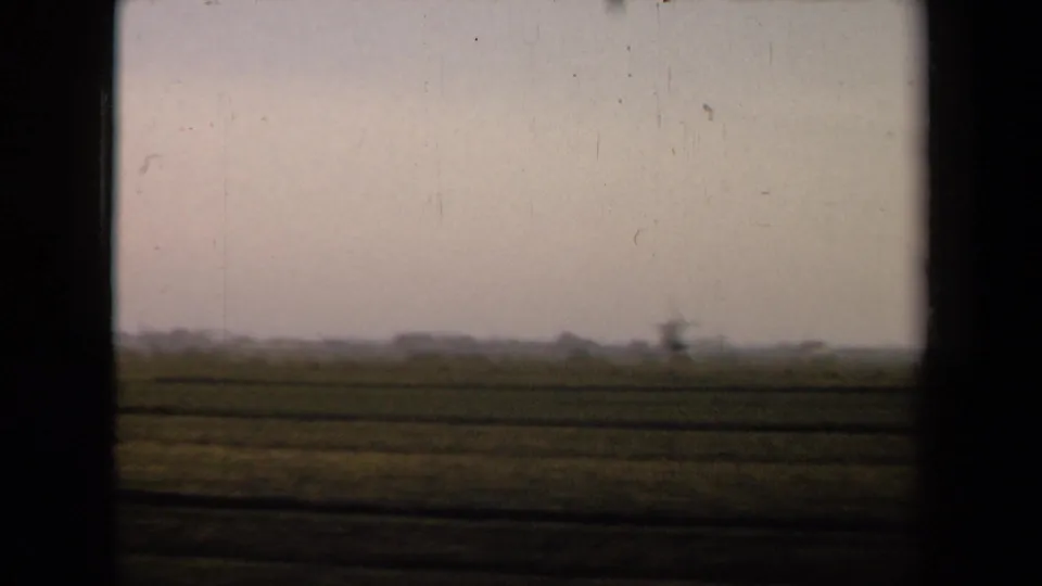 A 1946 Netherlands rural landscape shows low fields under a pale sky, with a windmill-like structure faintly visible on the horizon.