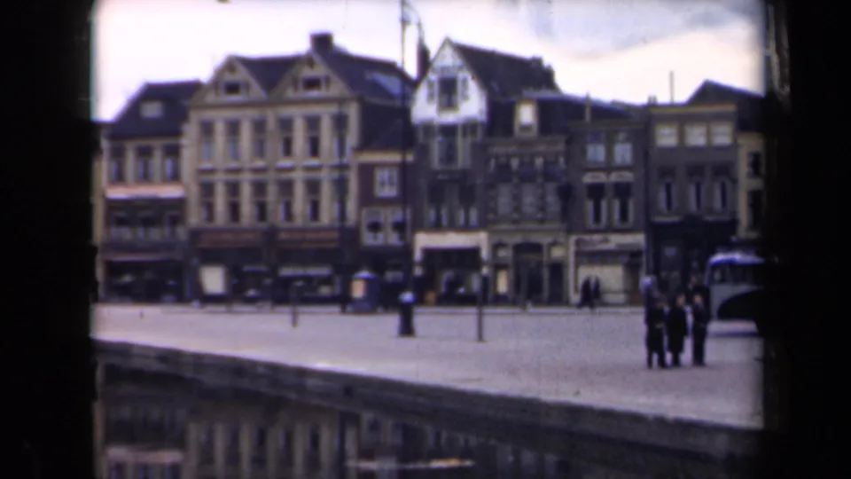 1946 Netherlands waterfront view with historic-looking gabled facades, pedestrians on the open quay, and a bus partly visible at the right.