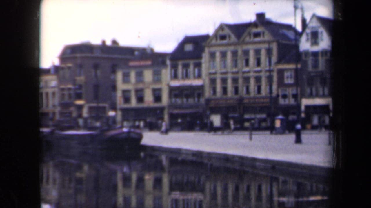 Historic canal-front buildings, pedestrians, and a dark boat beside the quay.