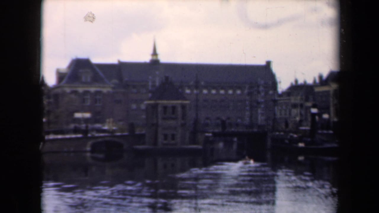 Canal view with historic buildings, a spired roofline, and reflections on the water.