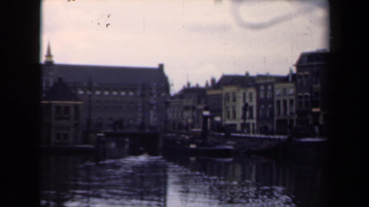 1946 Netherlands 8mm frame showing a canal lined with traditional buildings under an overcast sky.