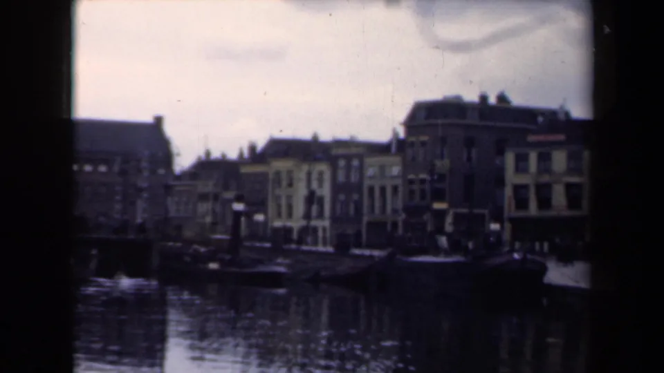 1946 Netherlands home-movie frame with canal water, moored boat, and closely spaced town buildings.