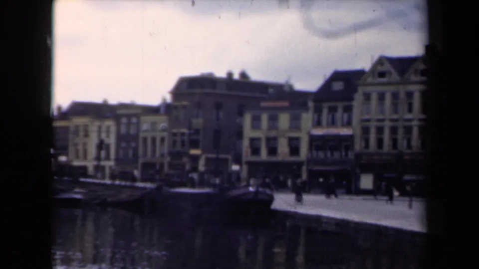 Dutch canal scene from 1946 showing moored boats, pedestrians on the quay, and tall gabled waterfront buildings.