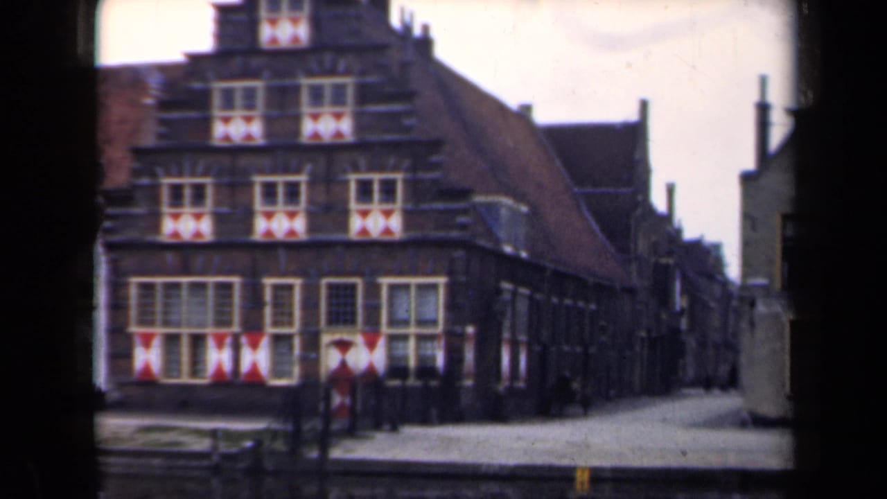 Gabled building and adjoining alley seen from across a paved street.