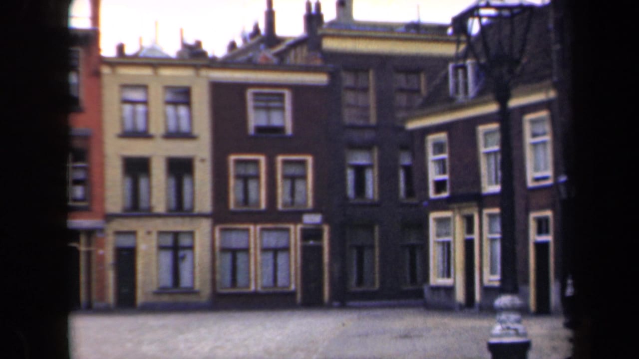Row of narrow townhouses with ochre and brown facades beside an empty street.