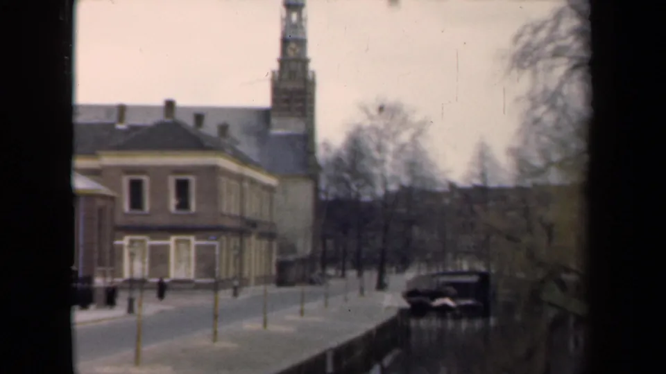 1946 Netherlands frame with the brick building and tower more centered beside the canal and parked car.