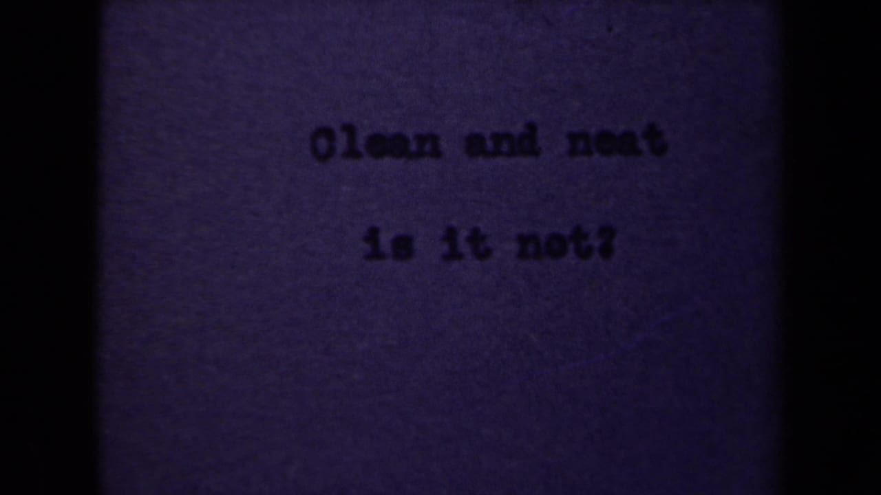 1946 Netherlands 8mm frame showing the typed phrase Clean and neat is it not? on purple-tinted paper with dark gate edges.