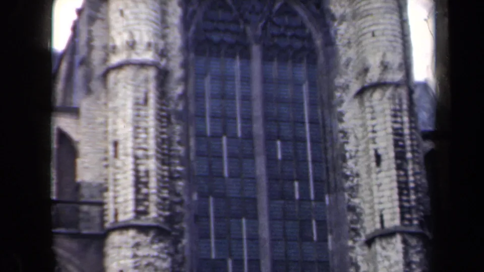 1946 Netherlands 8mm frame showing an arched Gothic-style window area with tracery, pale stone columns, and dark glass panels.