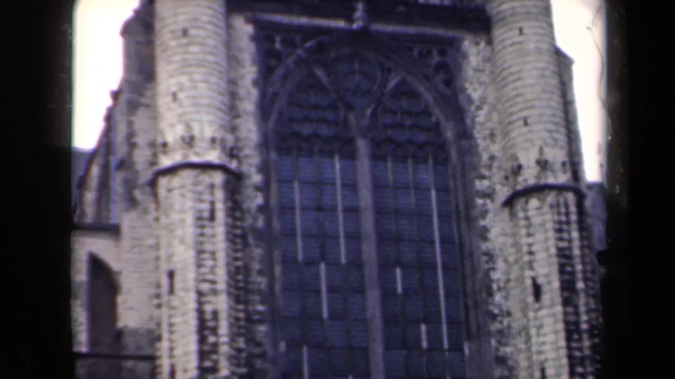 1946 Netherlands 8mm frame showing a Gothic-style façade with pale vertical stone forms, a dark arched window, and roofline fragments.