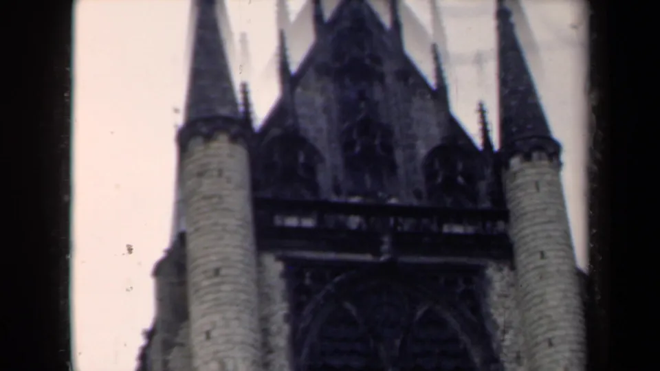 1946 Netherlands frame with the camera tilted upward toward cylindrical towers, spires, and Gothic facade details.