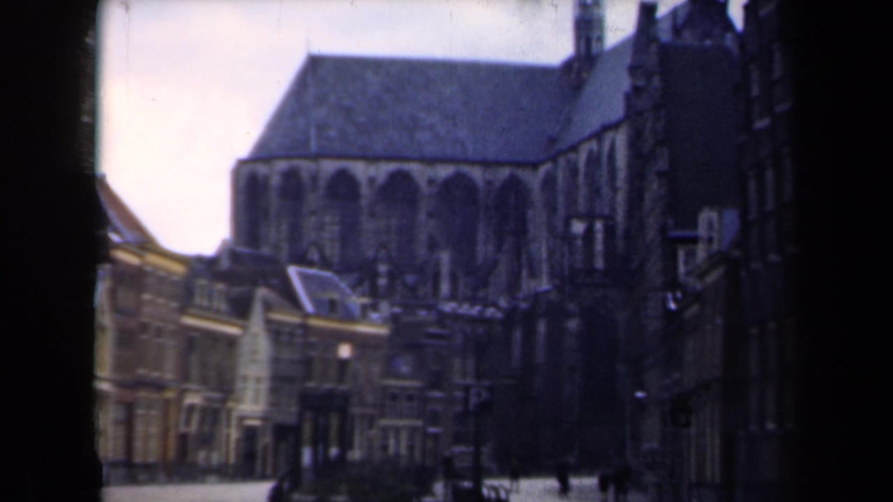 1946 Netherlands street view with a large Gothic church, traditional facades, and a few distant pedestrians under overcast light.